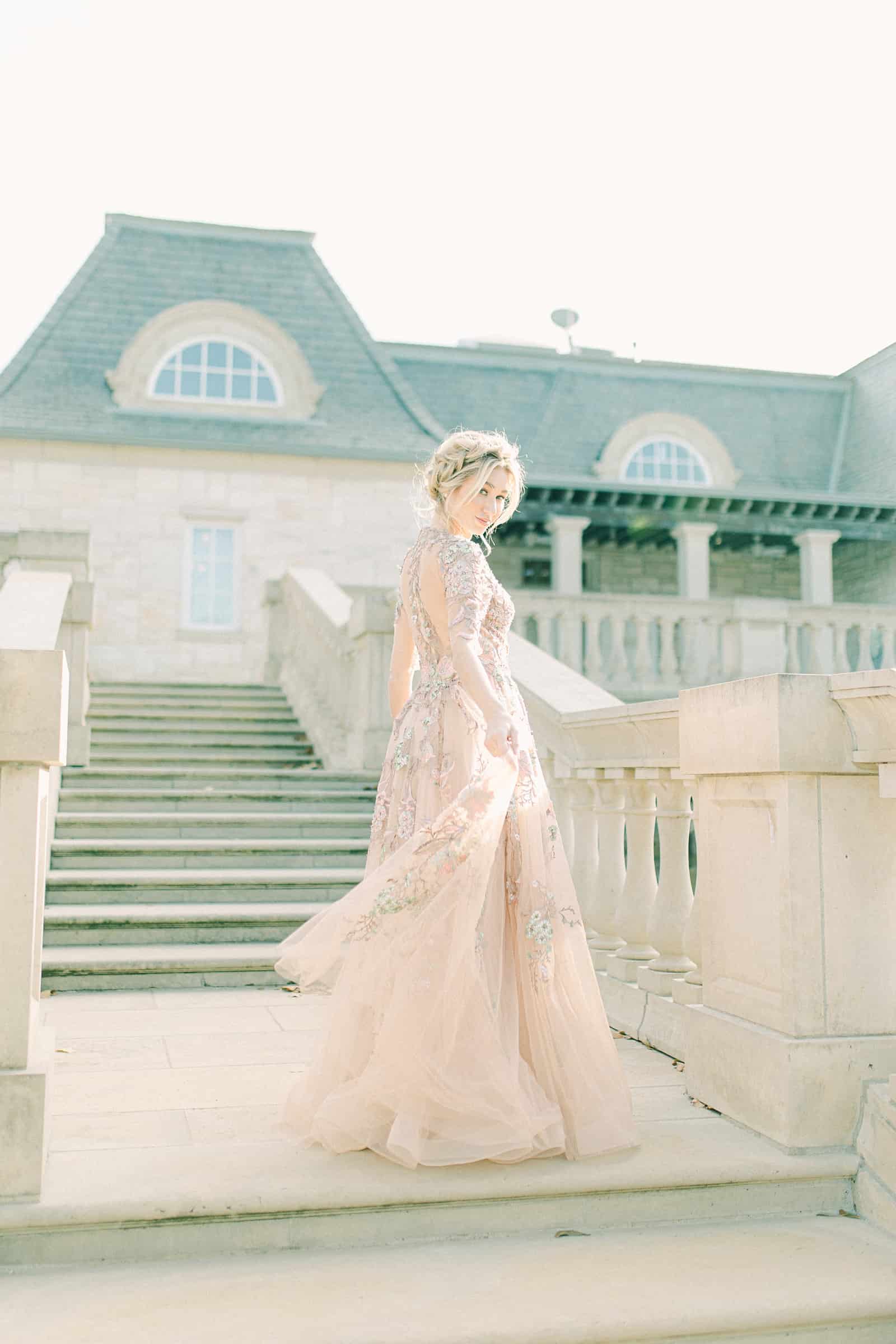 Bride walking down staircase wearing YSA Makino couture wedding dress with floral embellishments and embroidery, flowy wedding dress