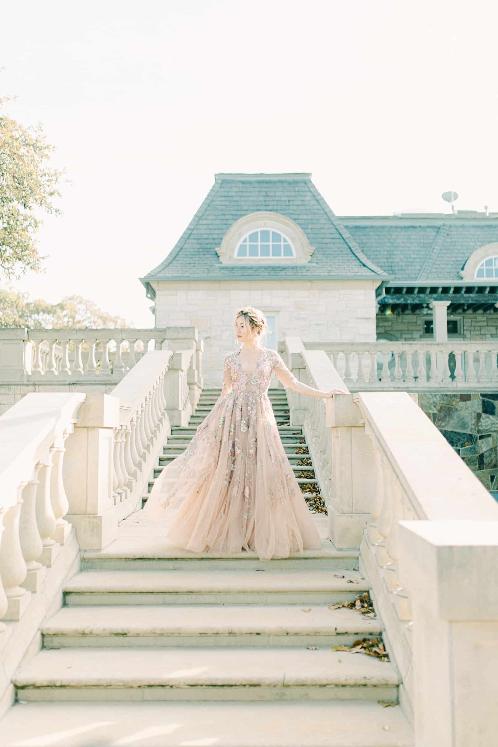 Bride walking down staircase wearing YSA Makino couture wedding dress with floral embellishments and embroidery, flowy wedding dress