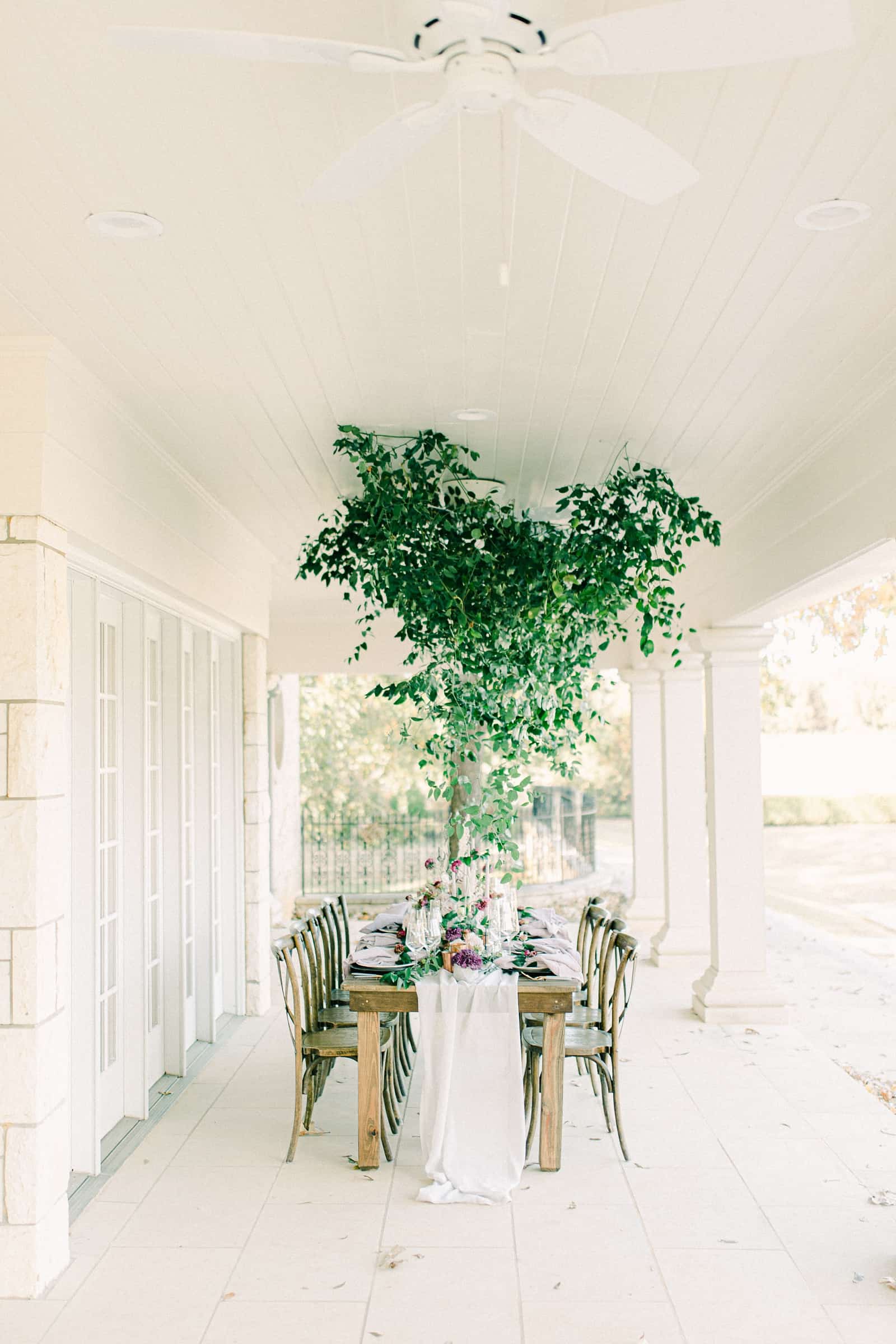 Wedding reception table for bridal party with canopy of greenery on ceiling