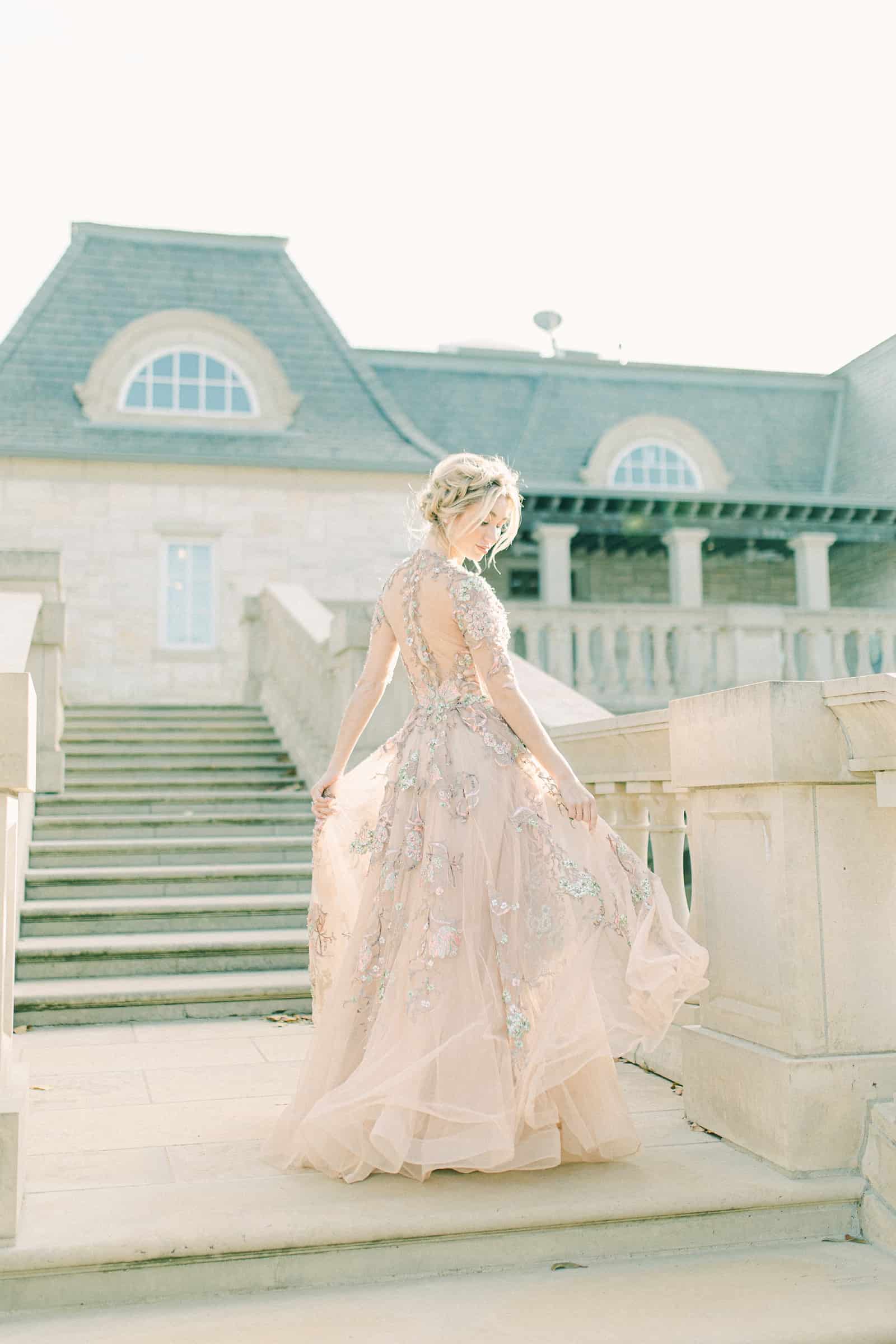 Bride walking down staircase wearing YSA Makino couture wedding dress with floral embellishments and embroidery, flowy wedding dress
