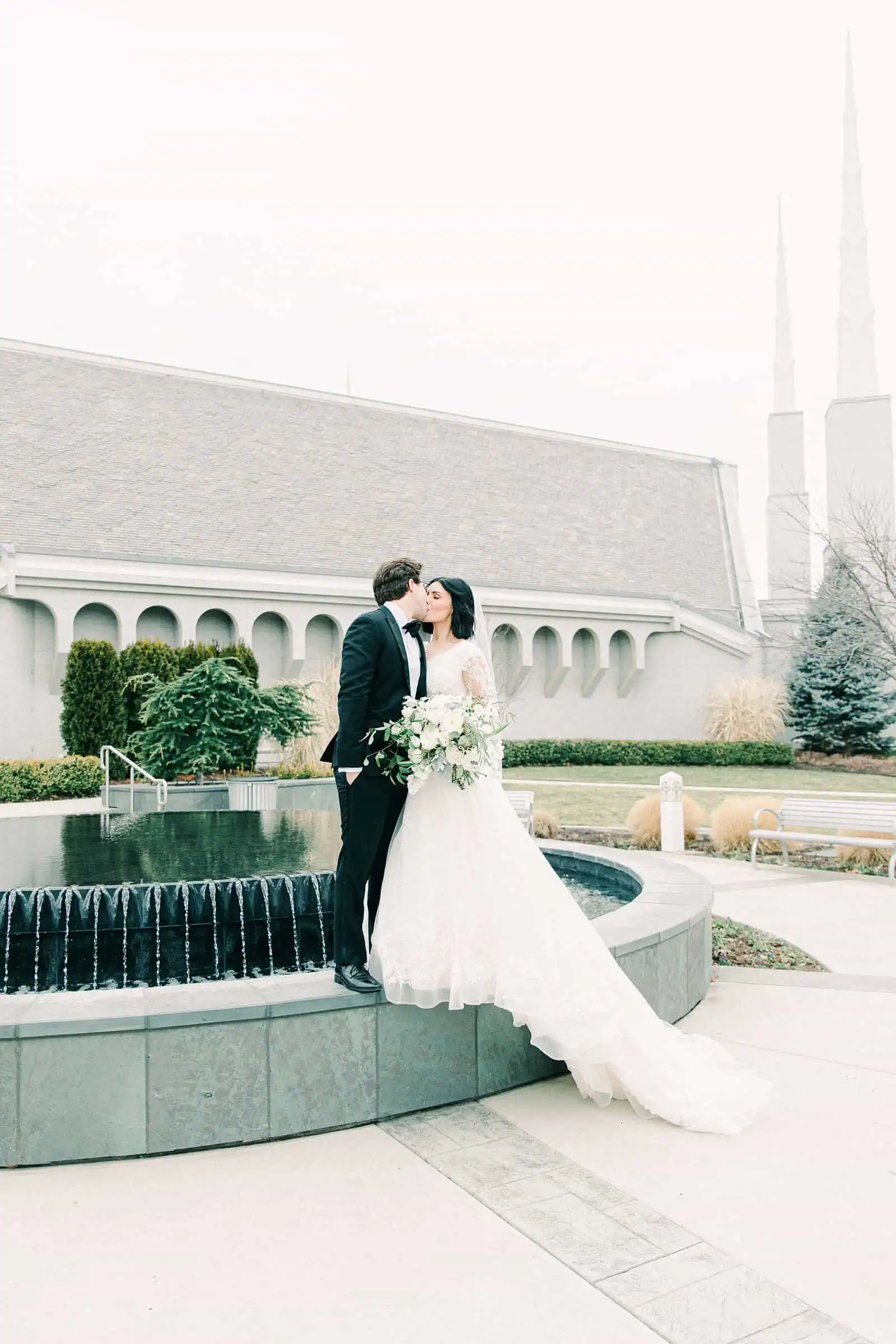 Boise LDS Temple wedding, bride and groom kiss in front of fountain winter wedding