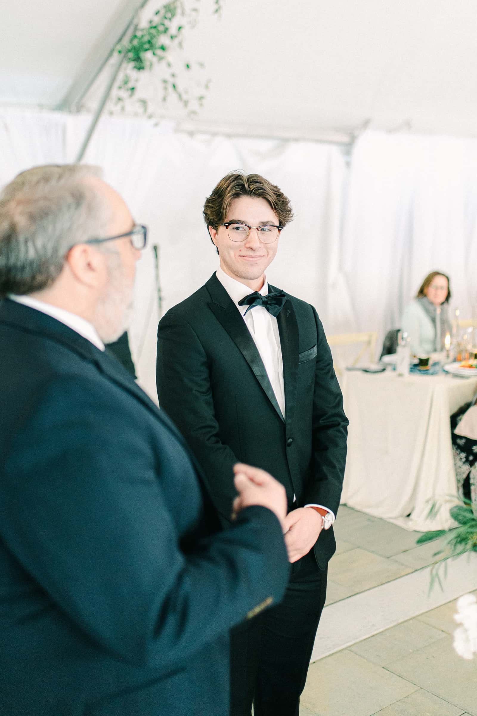 Winter wedding with white tent ceremony, groom looking at bride