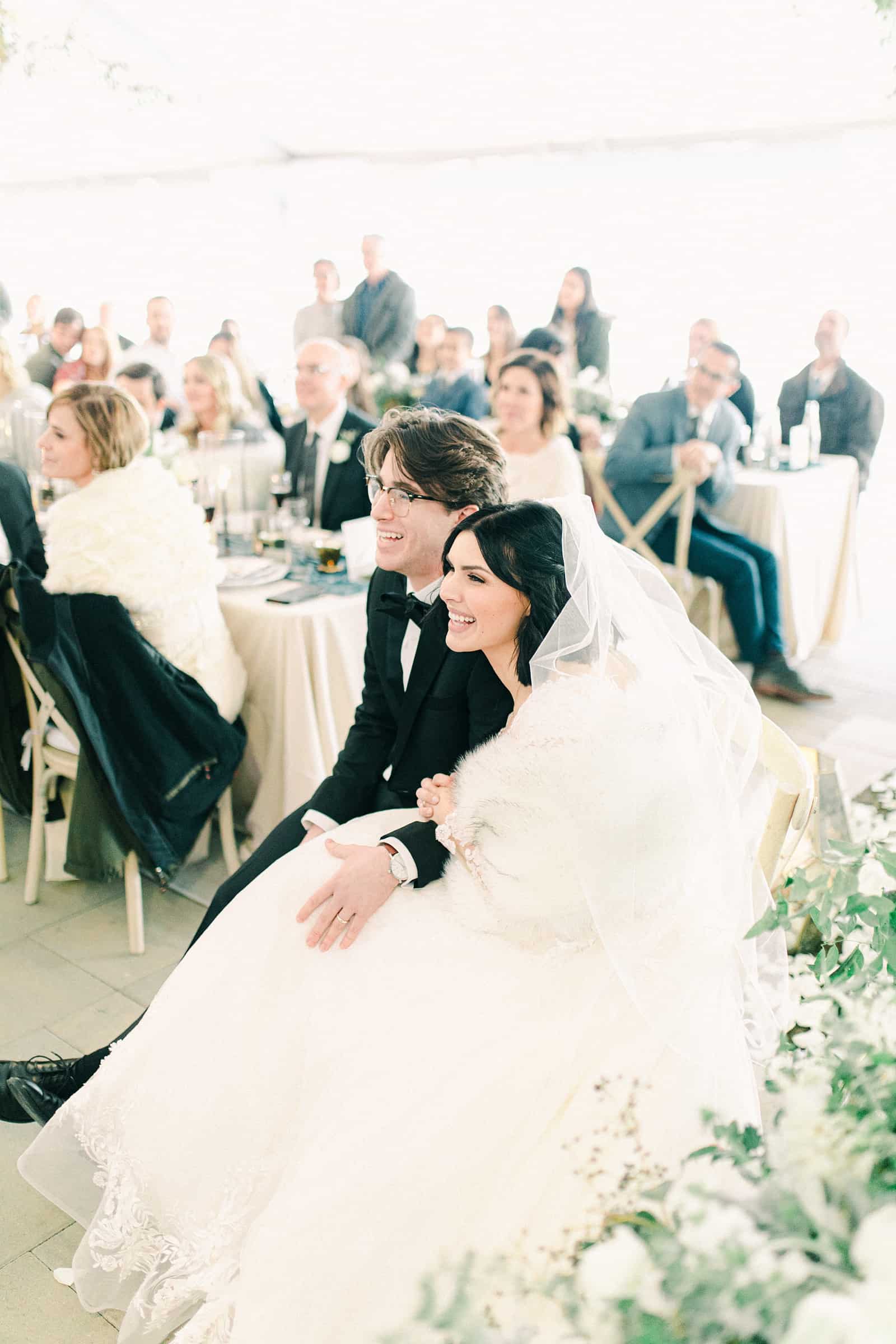 Bride and groom laughing during speeches at winter wedding reception