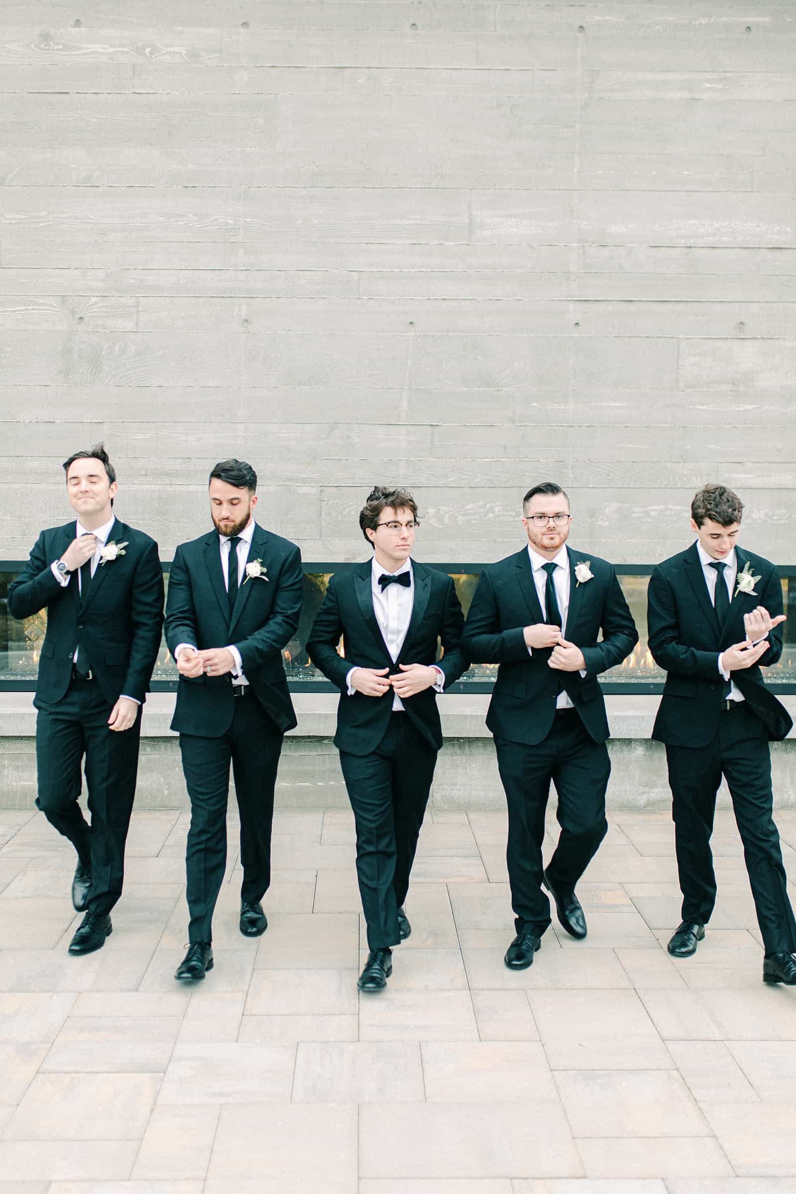 Groom and groomsmen in classic black tuxedos with bowties