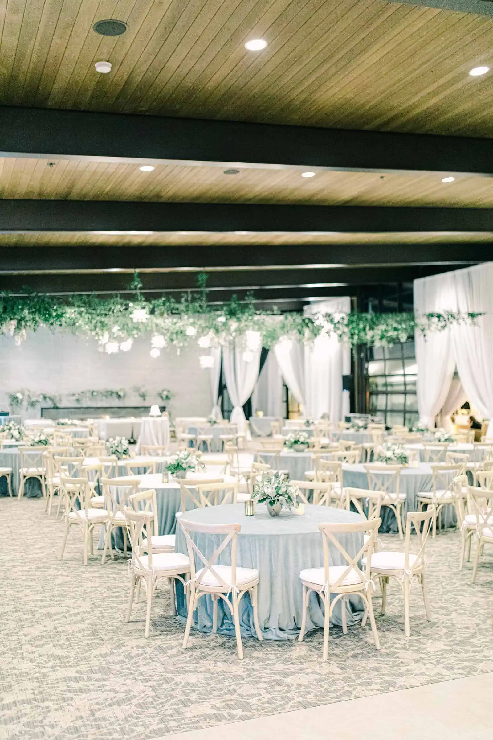 Luxury winter wedding inside white tent reception with greenery floral garland with white roses and tables with centerpieces