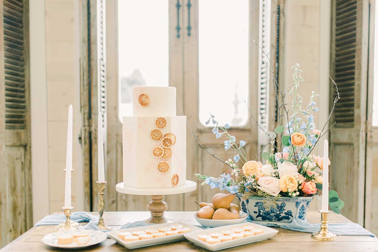 White buttercream wedding cake with two tiers and oranges clementines and flower centerpiece with pastel colors