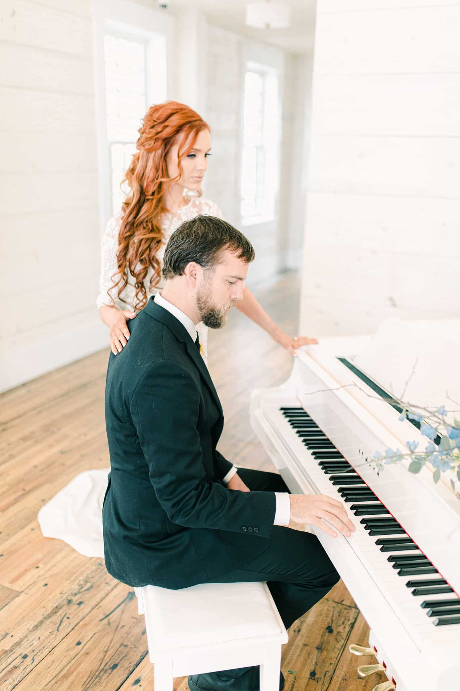 Groom plays white baby grand piano for bride on their wedding day