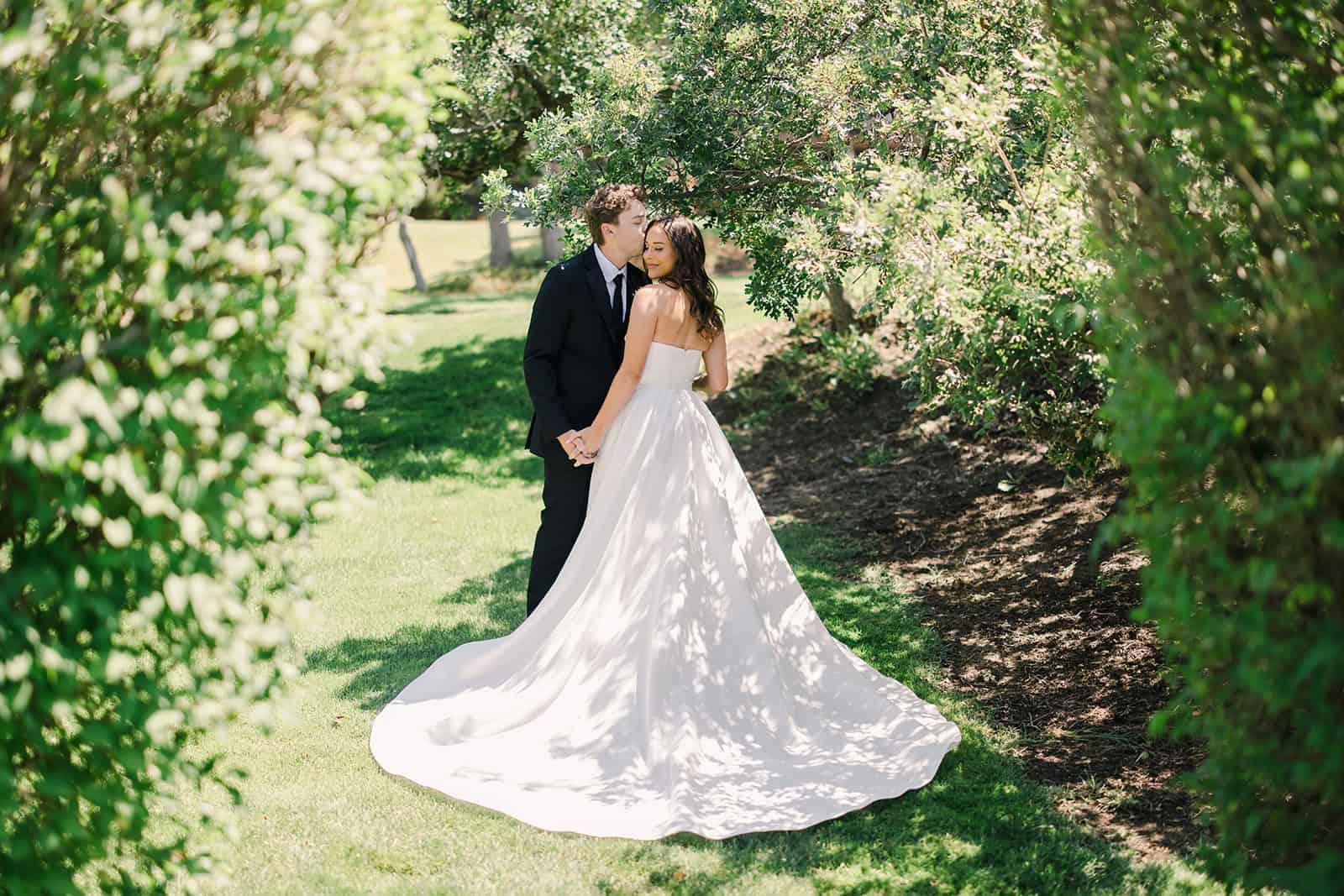 Elegant wedding photo of a bride and groom in a garden setting.