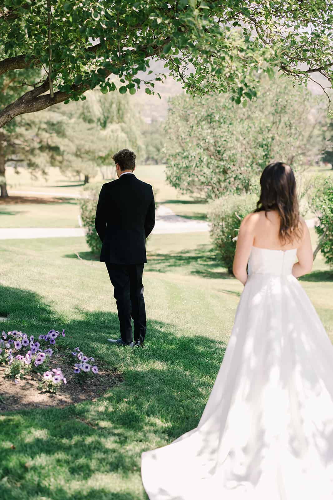 Elegant wedding couple in a lush green park setting.