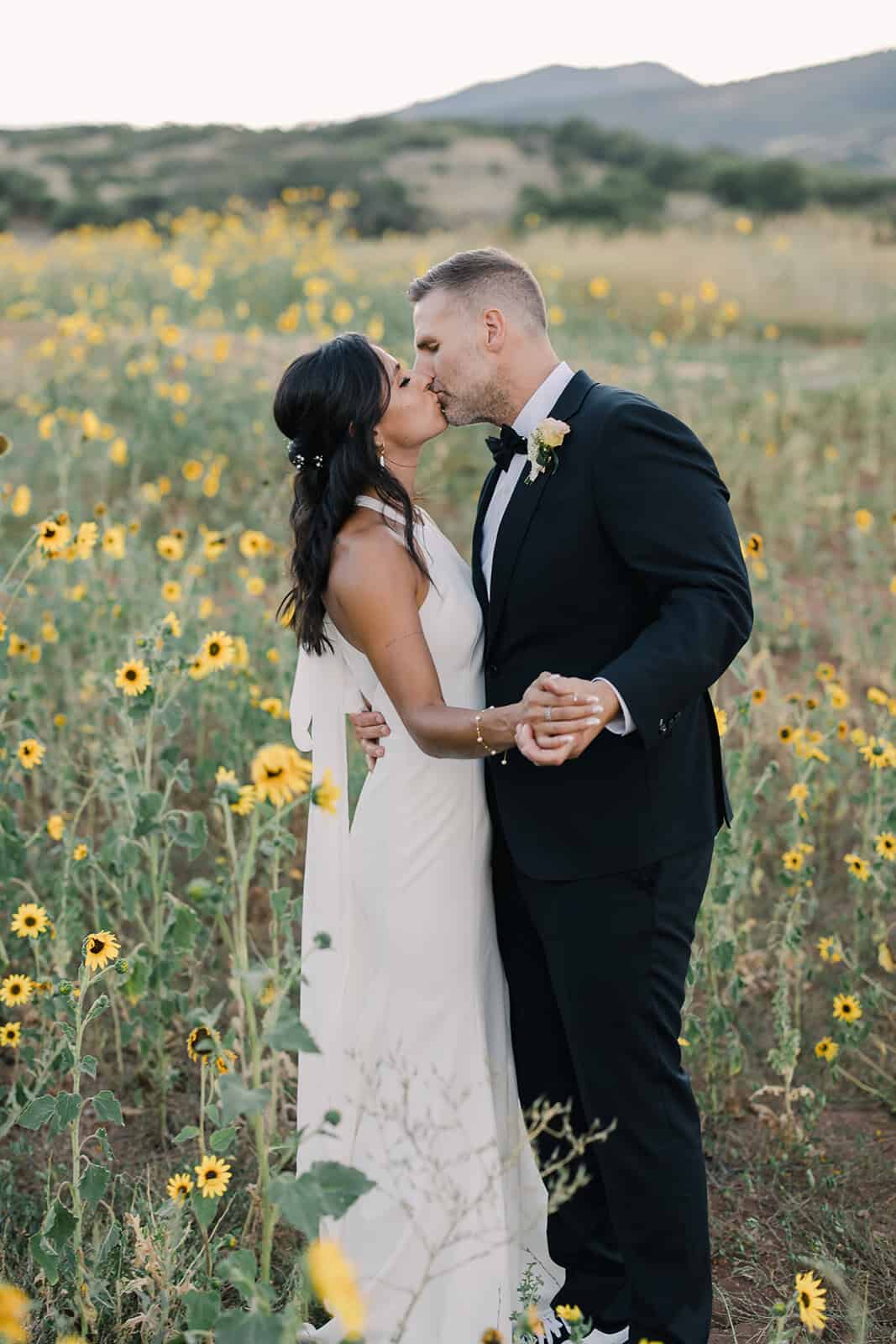 Wedding couple kissing in sunflower field.