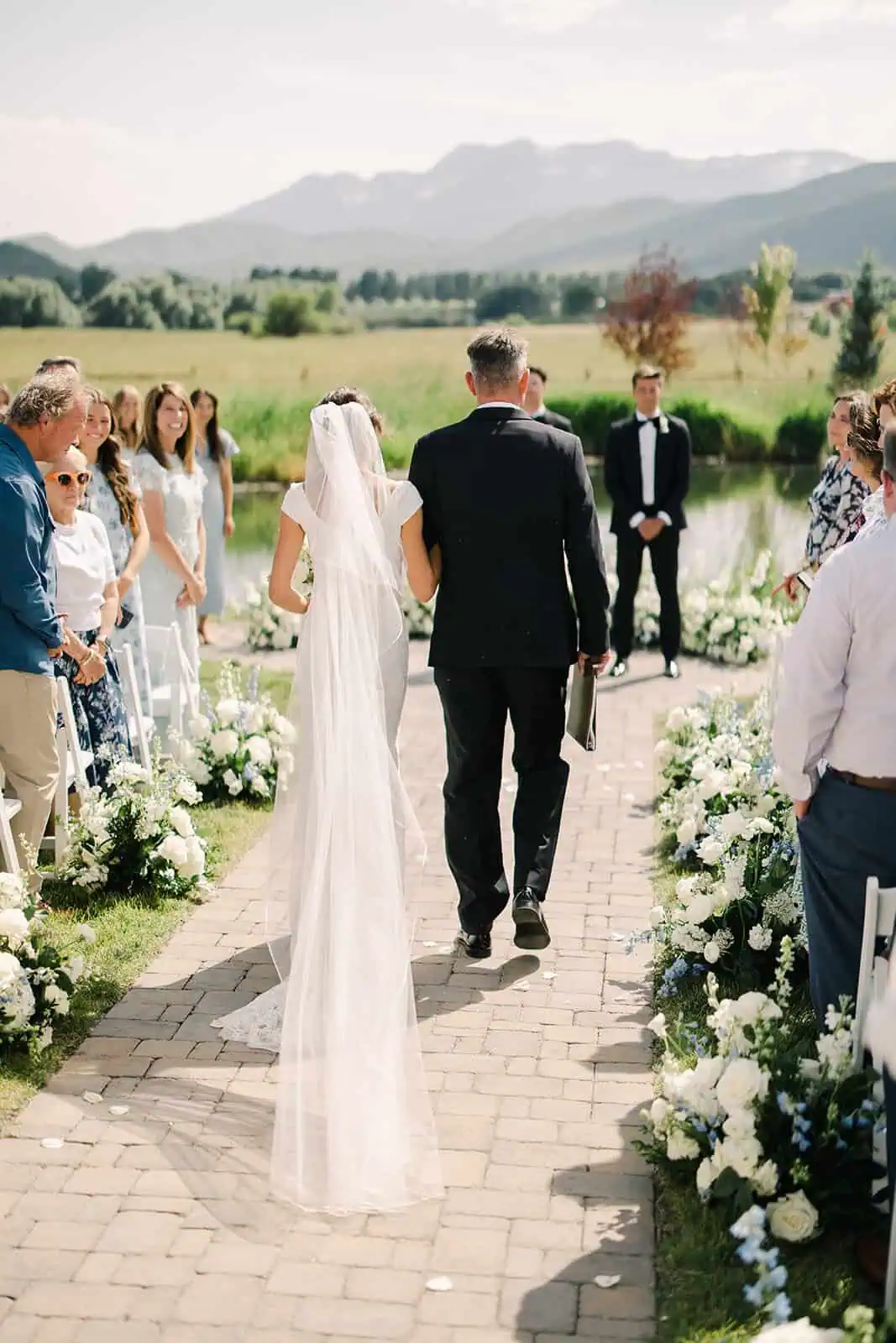 Bride and groom walking down the aisle surrounded by friends and family.