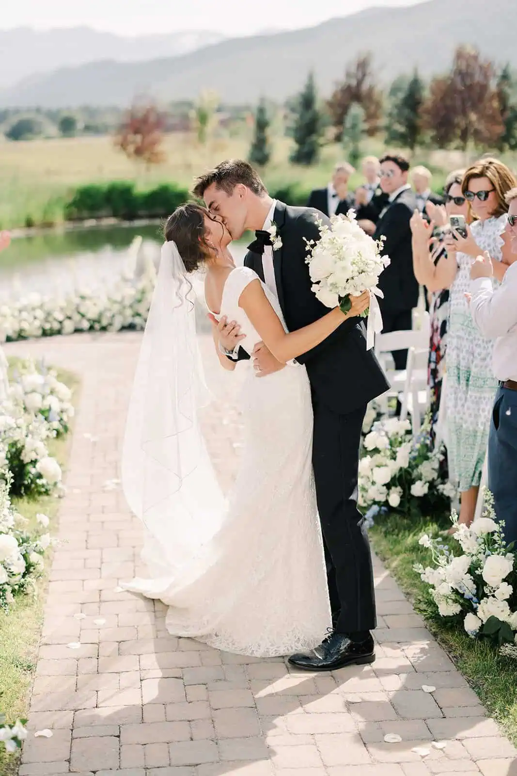Romantic wedding scene with bride and groom sharing a kiss during outdoor ceremony.