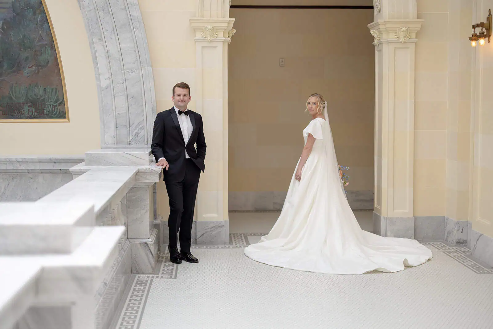 Bride and groom pose inside a grand, historic church with classical architecture and soft lighting.
