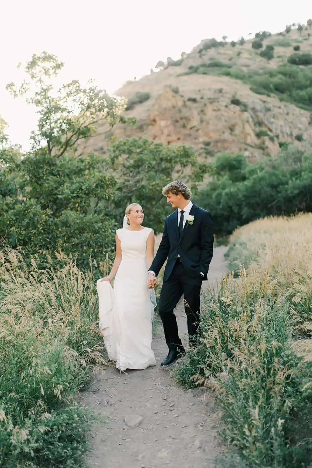 Elegant bride and groom walking hand in hand outdoors.