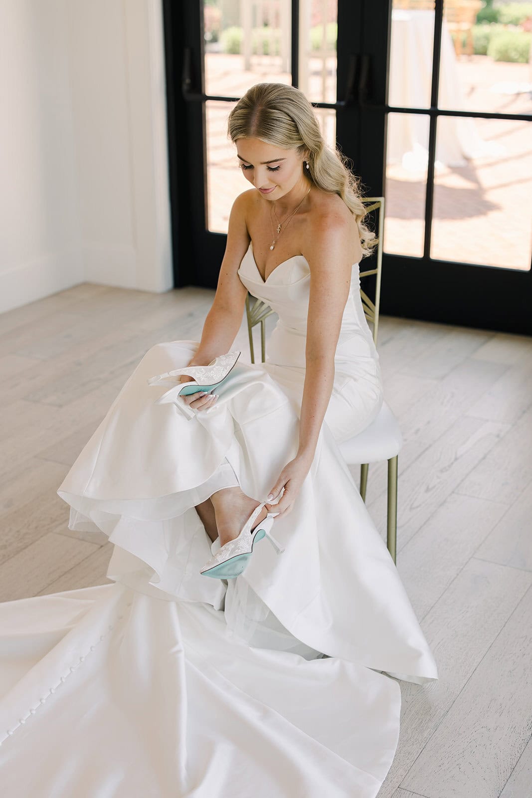 Elegant bride putting on her wedding shoes in a bright, modern venue.