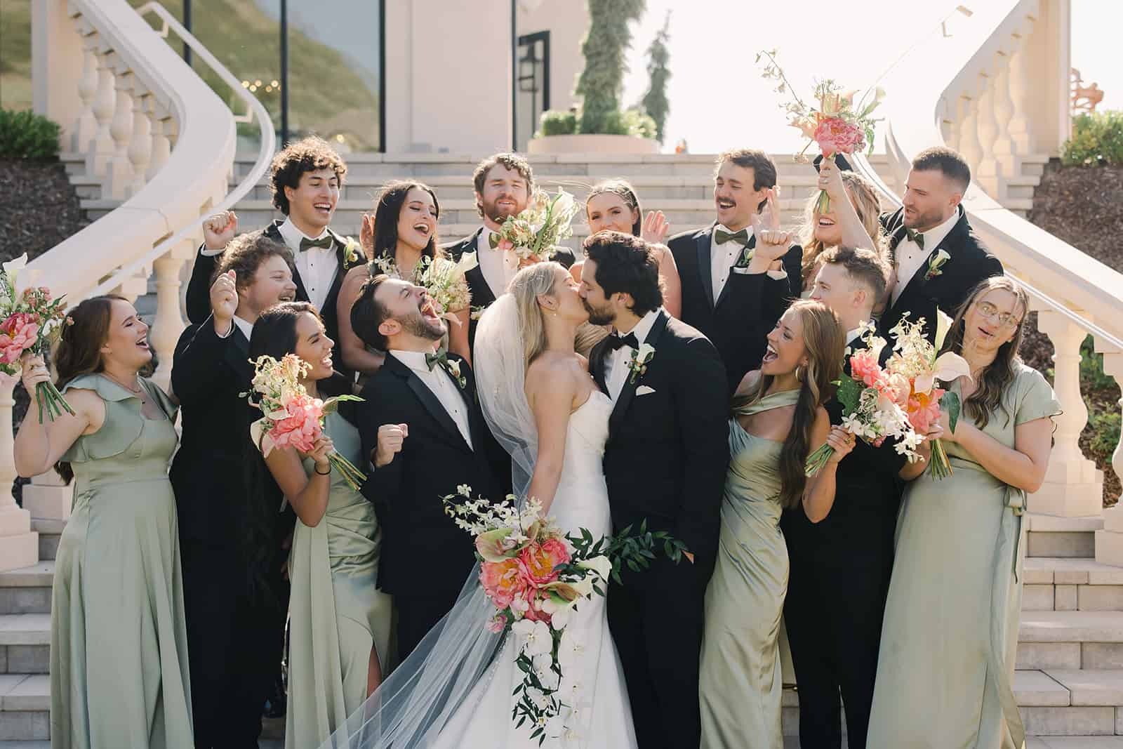 Wedding celebration with bride and groom surrounded by friends and family on outdoor staircase.