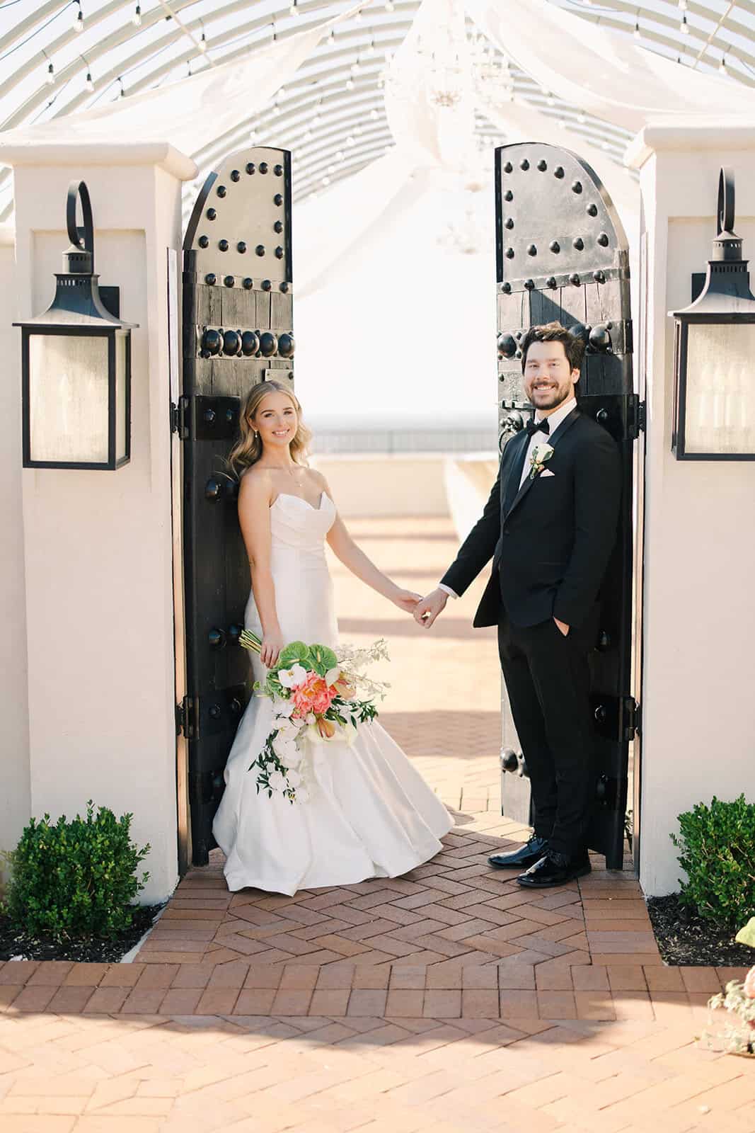 Wedding couple holding hands at elegant venue entrance.