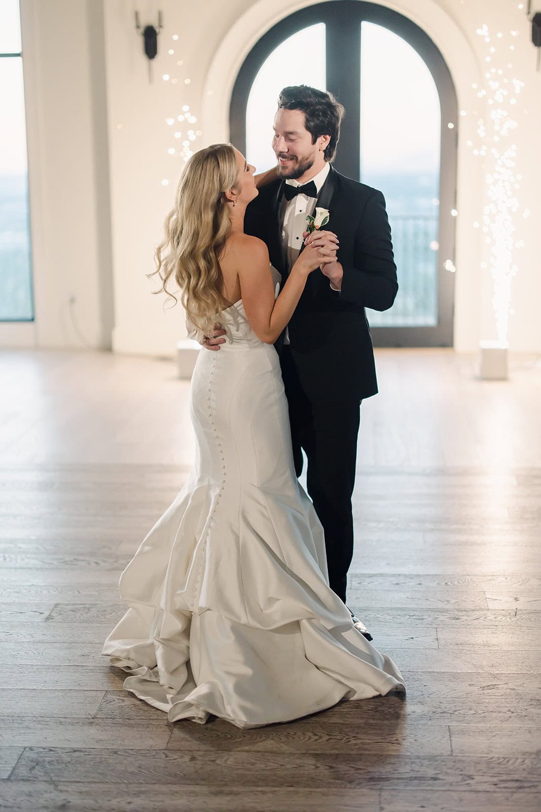 Bride and groom sharing a romantic dance in a bright, stylish reception hall.