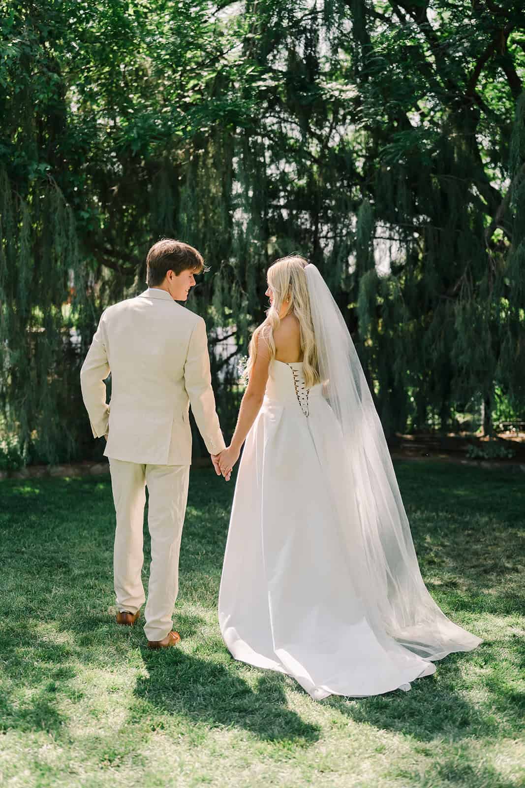 Bride and groom holding hands in a scenic garden.