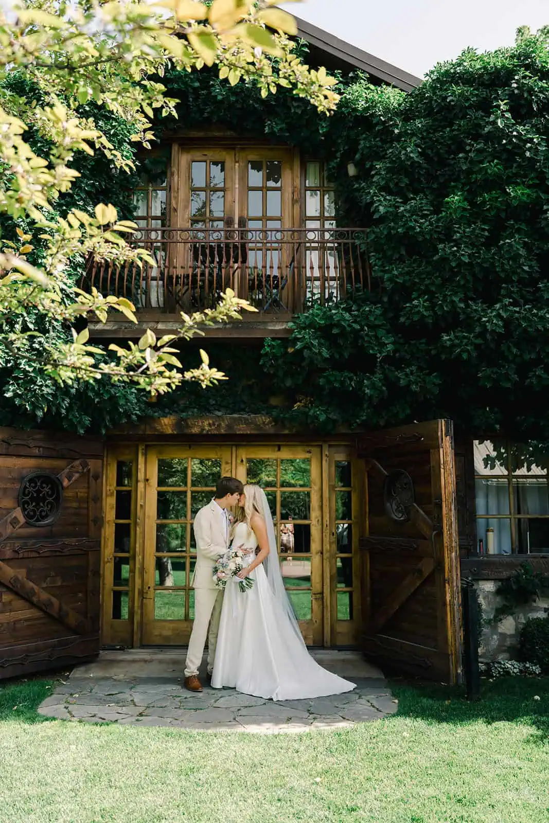 Romantic wedding photo of a bride and groom embracing outside a rustic wooden cabin.