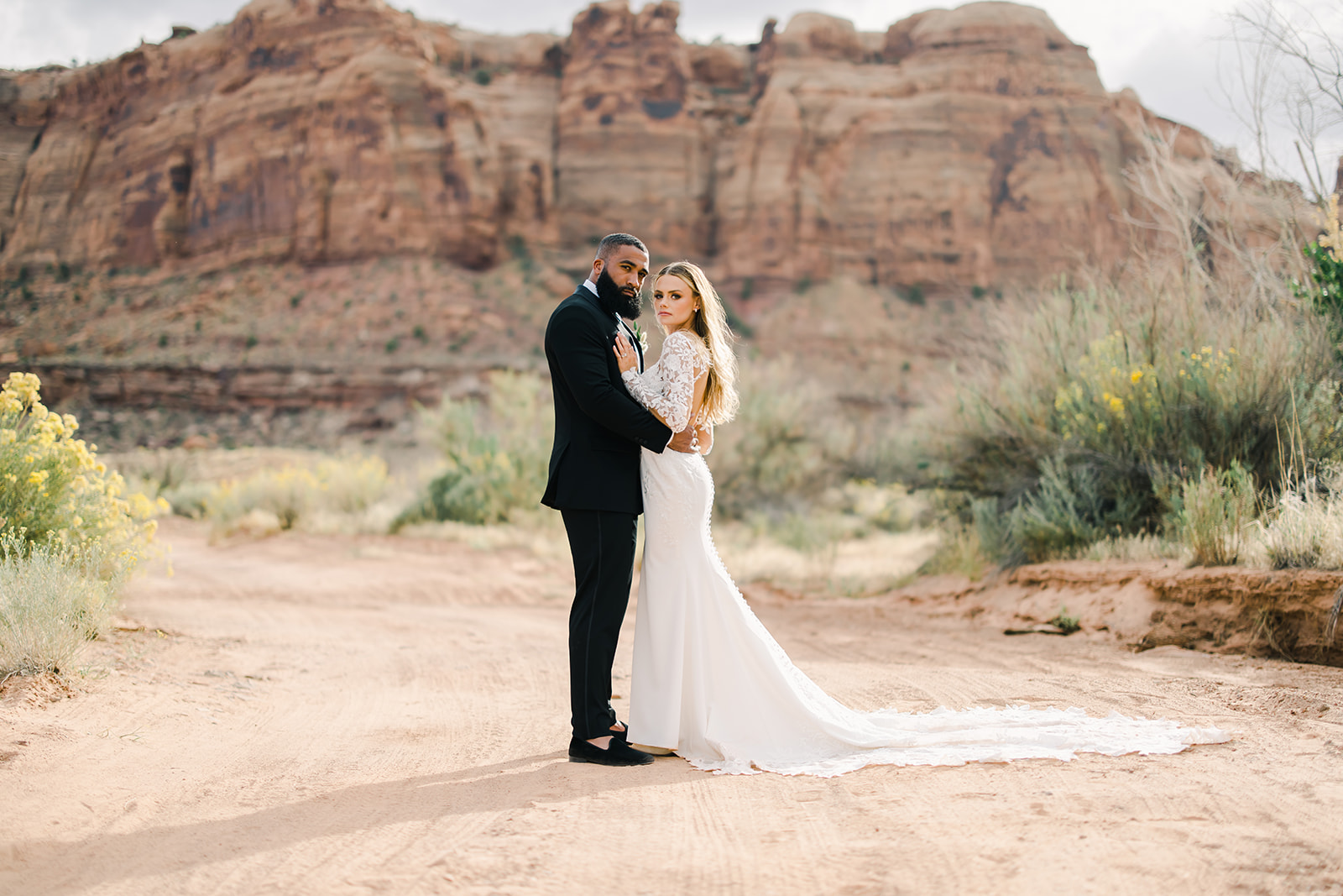 Bride and Groom Embrace in Desert Near Red Earth Venue Moab